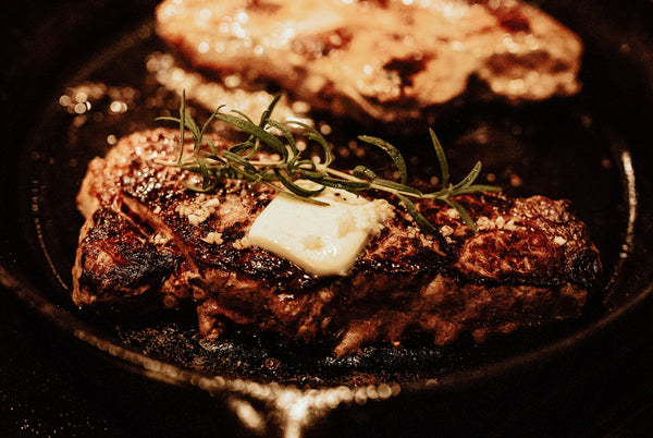 Picture of a steak in a pan with butter and rosemary