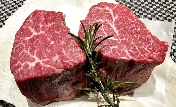 Japanese A5 Wagyu tenderloin steaks with thyme on a piece of paper